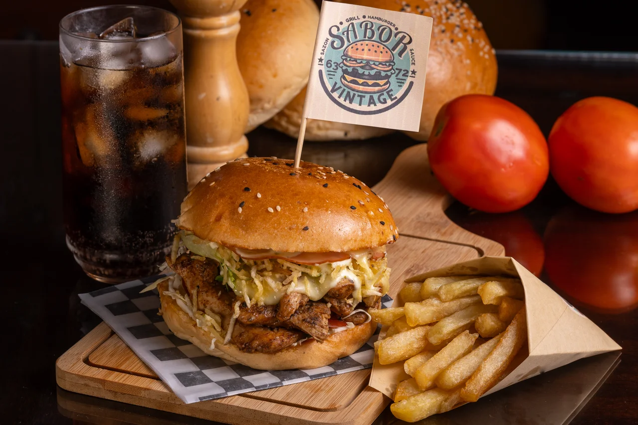 Hamburguesa y papas con luz lateral cálida, textura nítida y marca legible