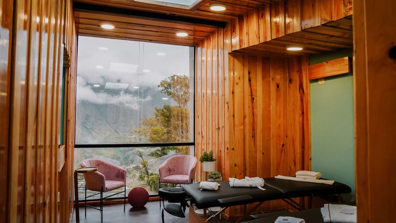 Spa revestido en madera con dos camillas, toallas y ventanal hacia las montañas