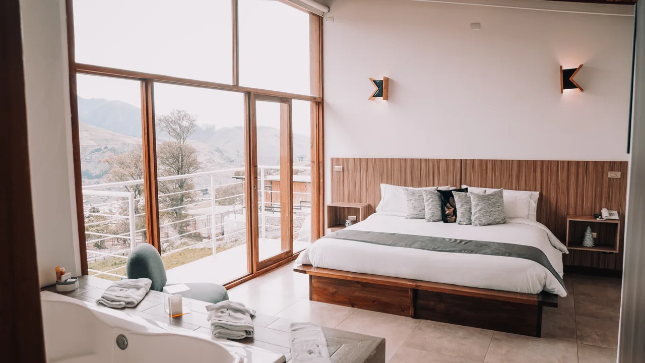 Habitación con cama, ventanales y vista de montaña