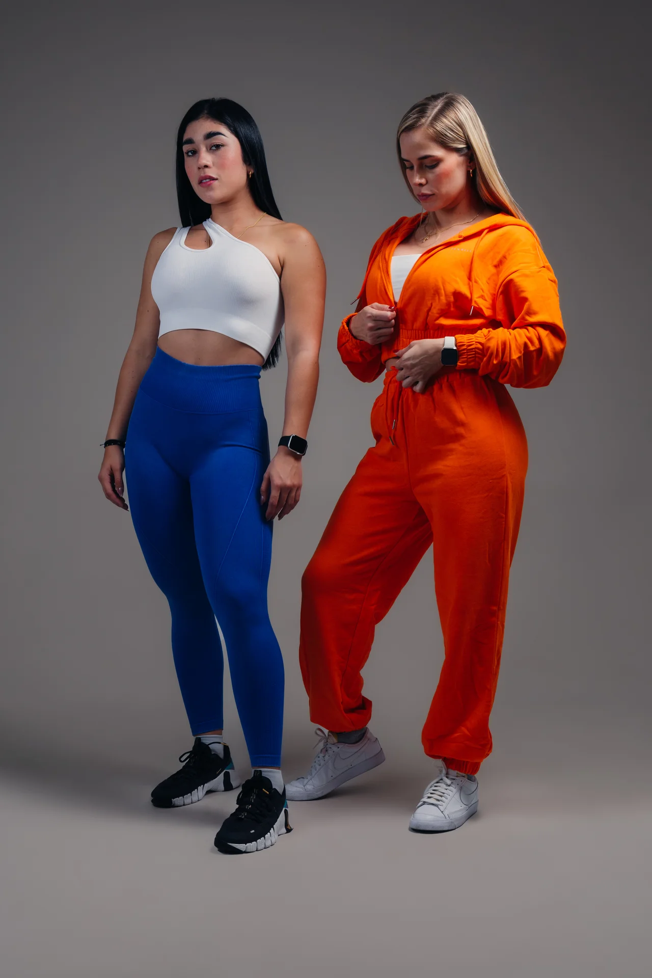 Dos modelos con ropa deportiva azul y naranja sobre gris