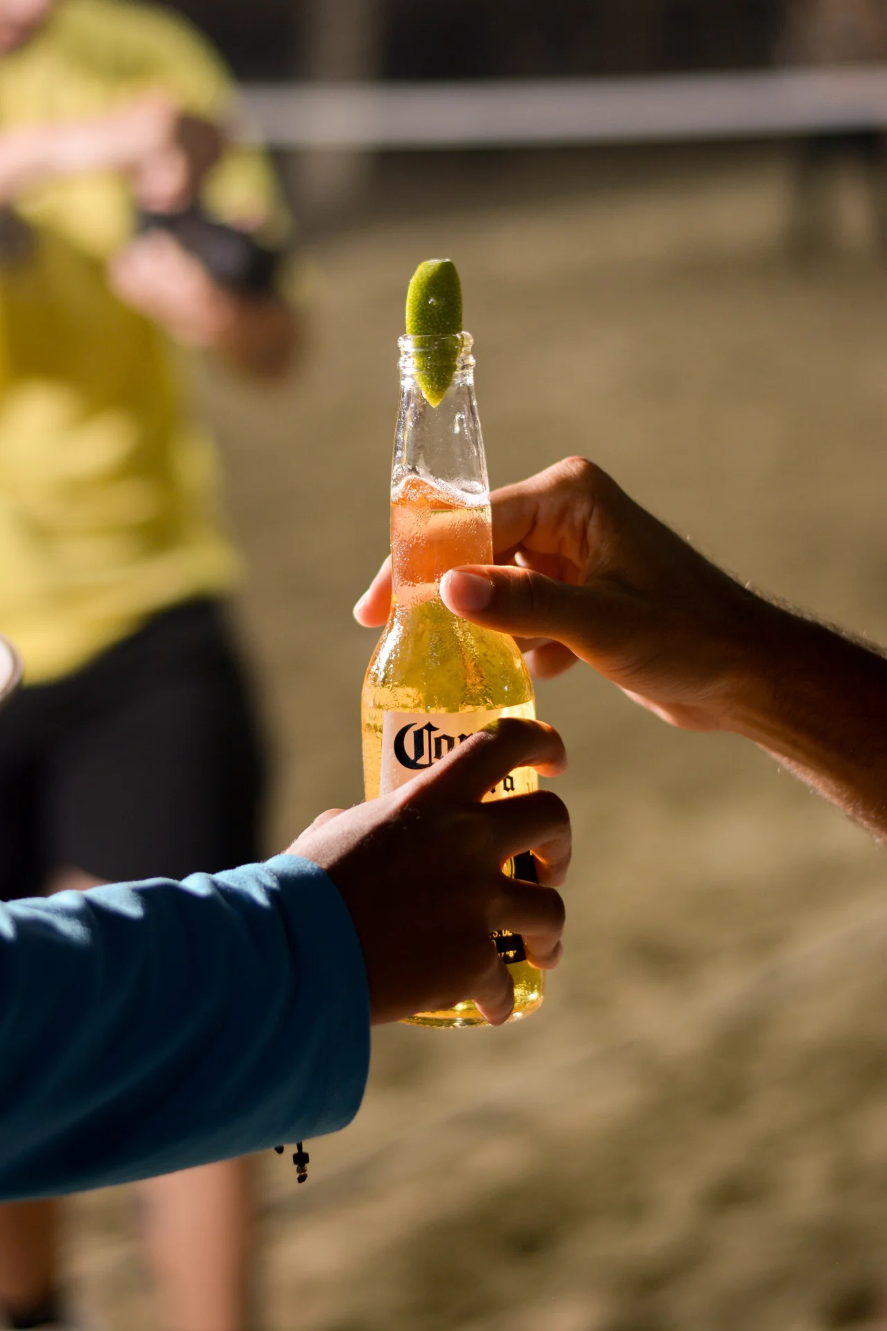 Dos manos sostienen una cerveza con limón en contraluz cálido