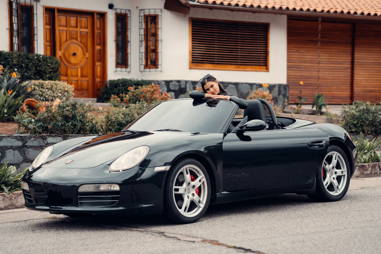 Modelo con convertible negro entero ante fachada de madera y jardín