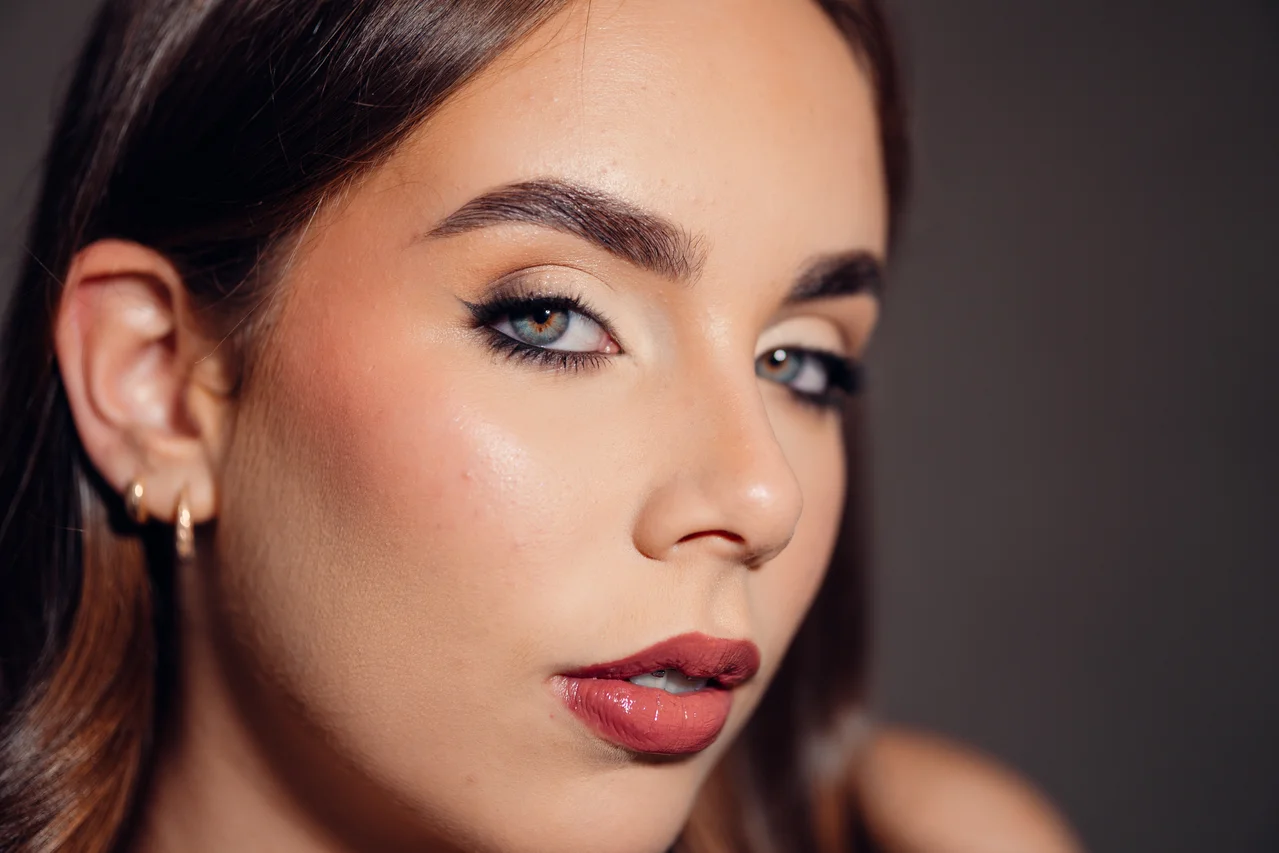 Primer plano horizontal de belleza con ojo próximo muy nítido, maquillaje limpio y fondo gris