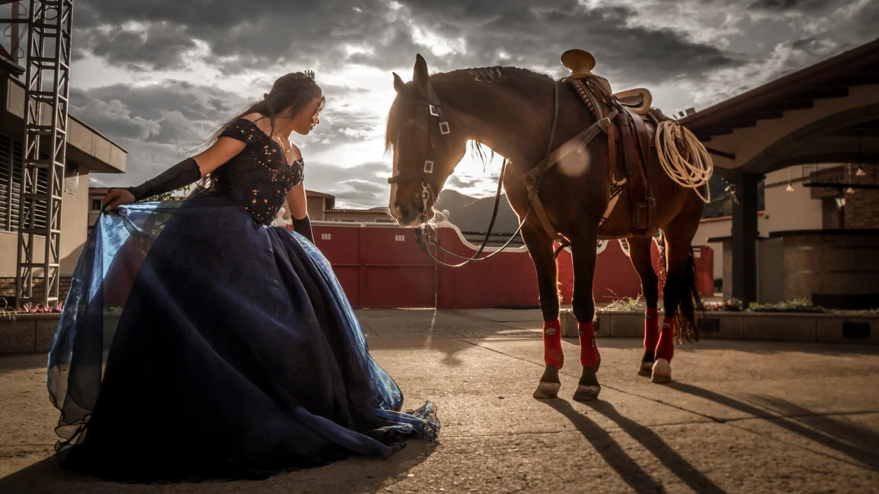 Plano amplio de quinceañera y caballo a contraluz
