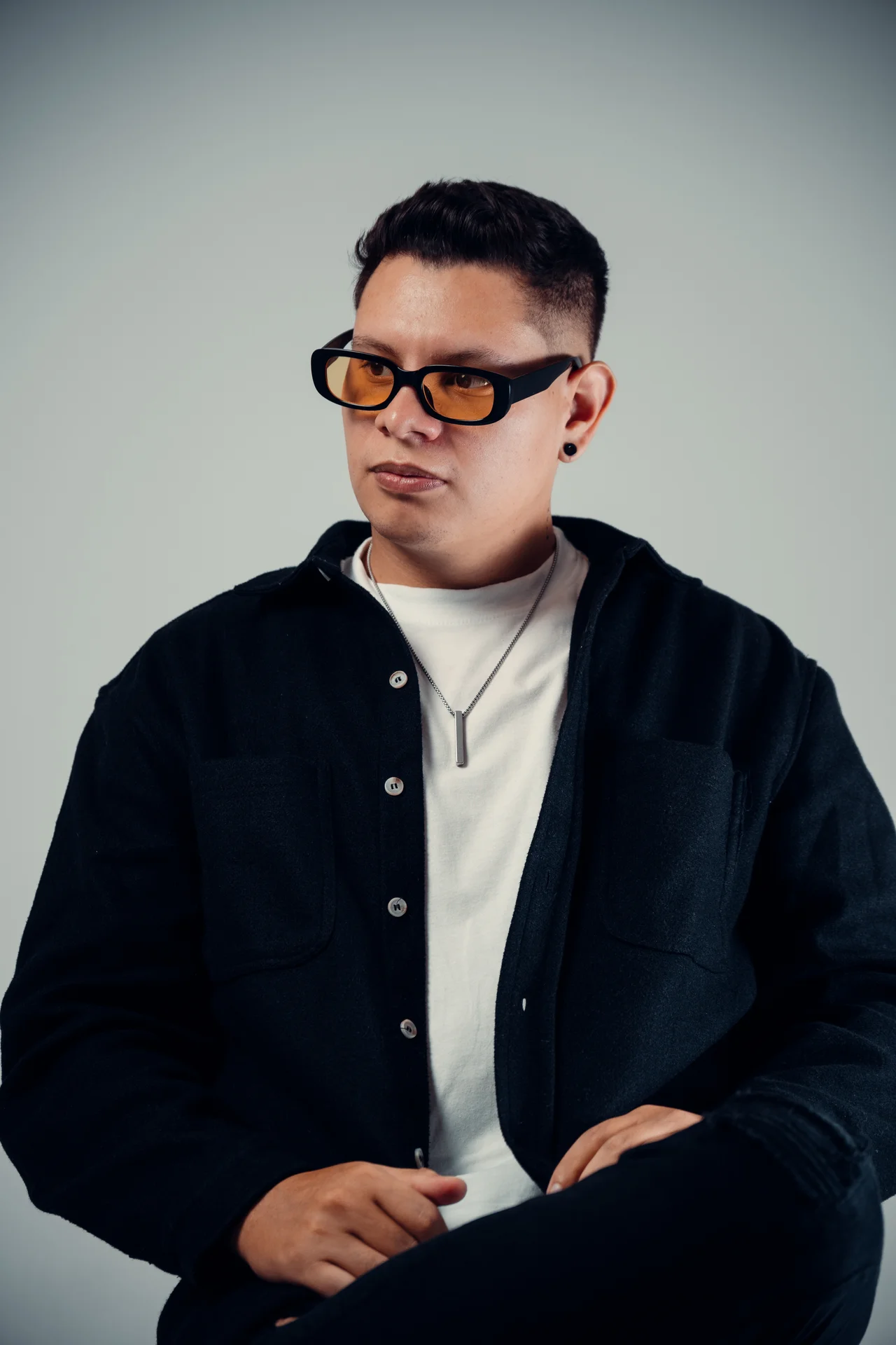 Retrato de artista con lentes ámbar, blanco y negro del vestuario y fondo gris limpio