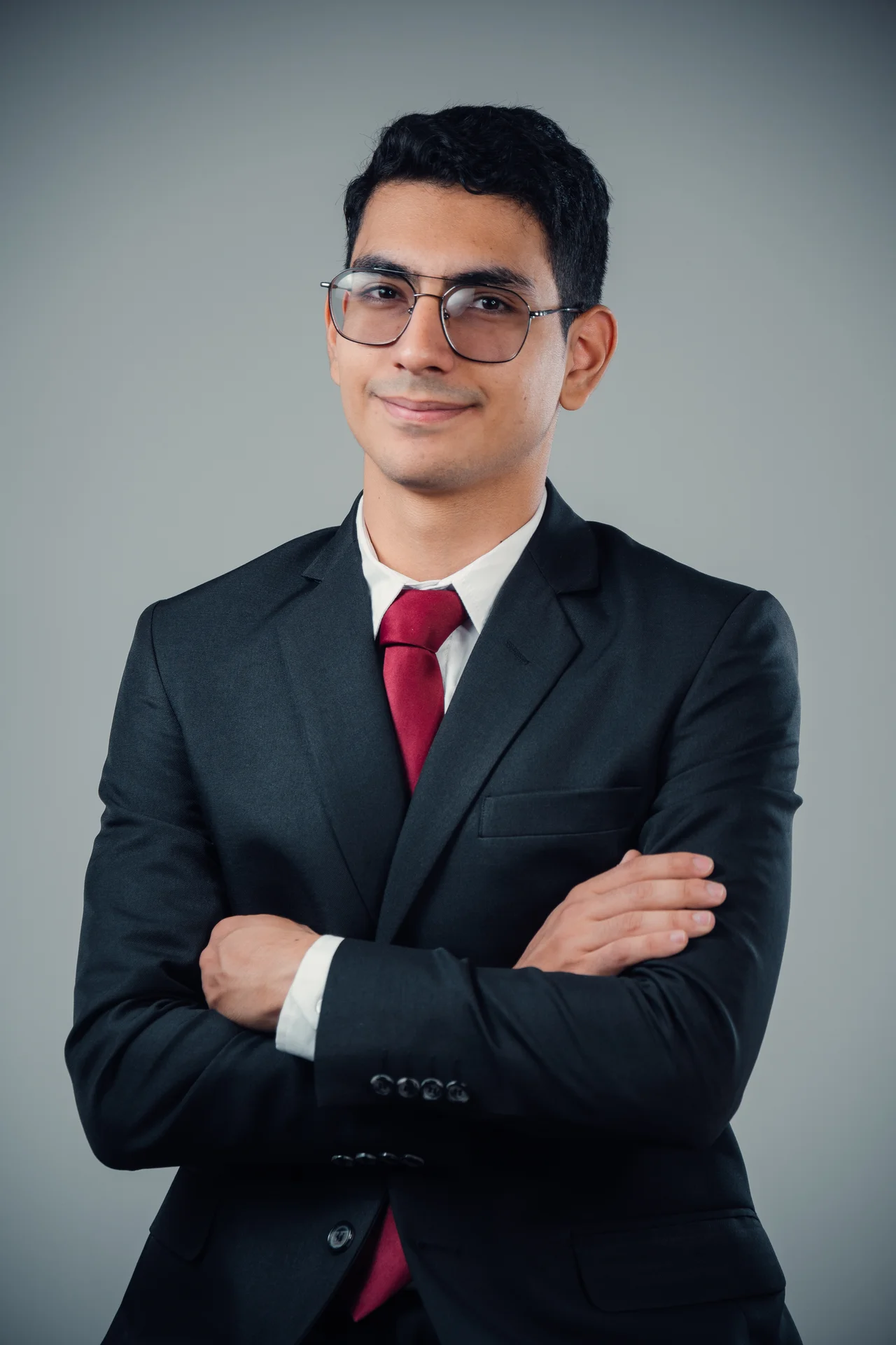 Retrato profesional con traje, brazos cruzados y fondo gris limpio