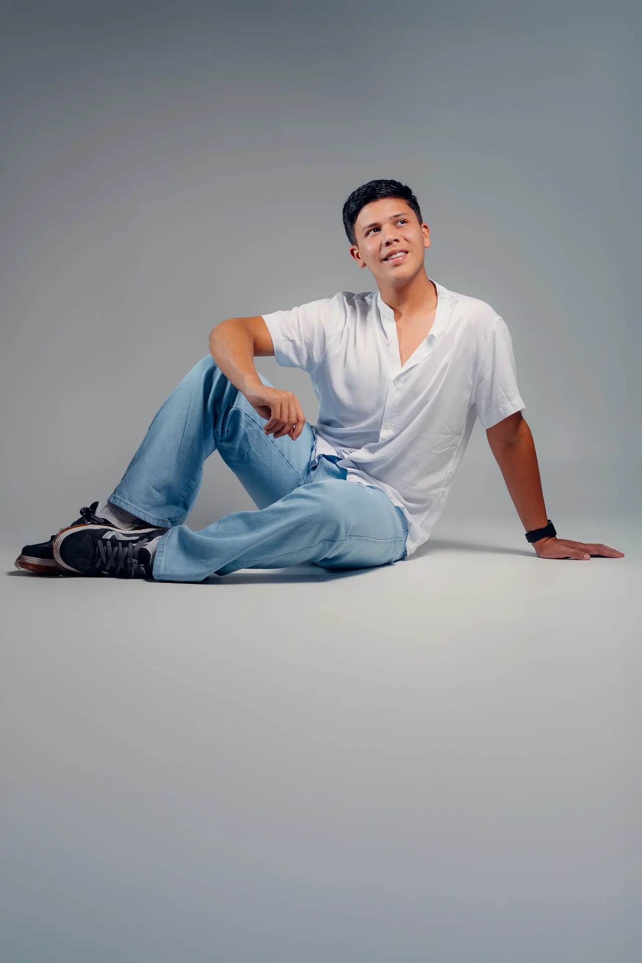Retrato masculino sentado en fondo gris con espacio negativo
